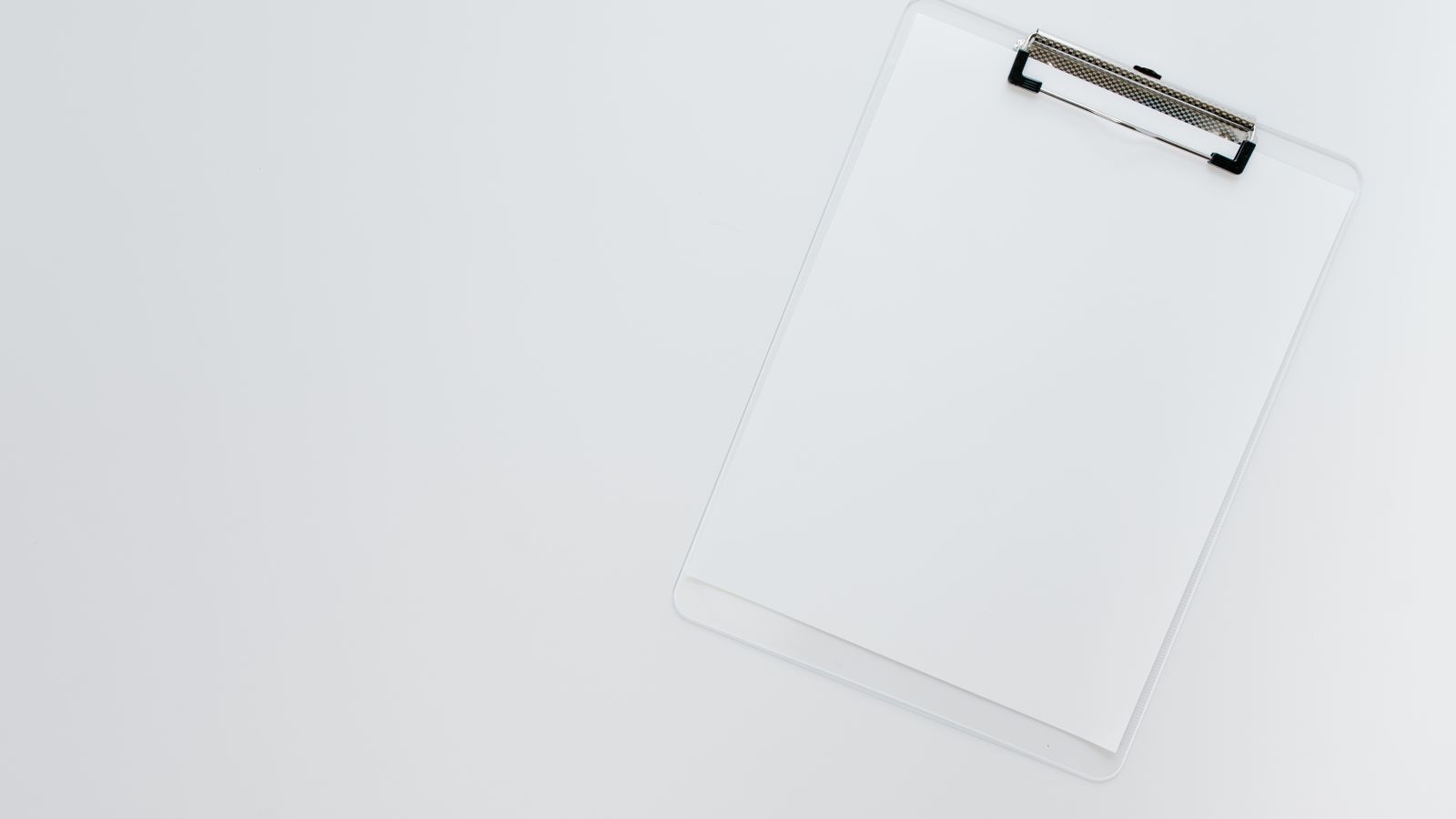 Minimalist top view of a transparent clipboard on a white background offering ample copy space.