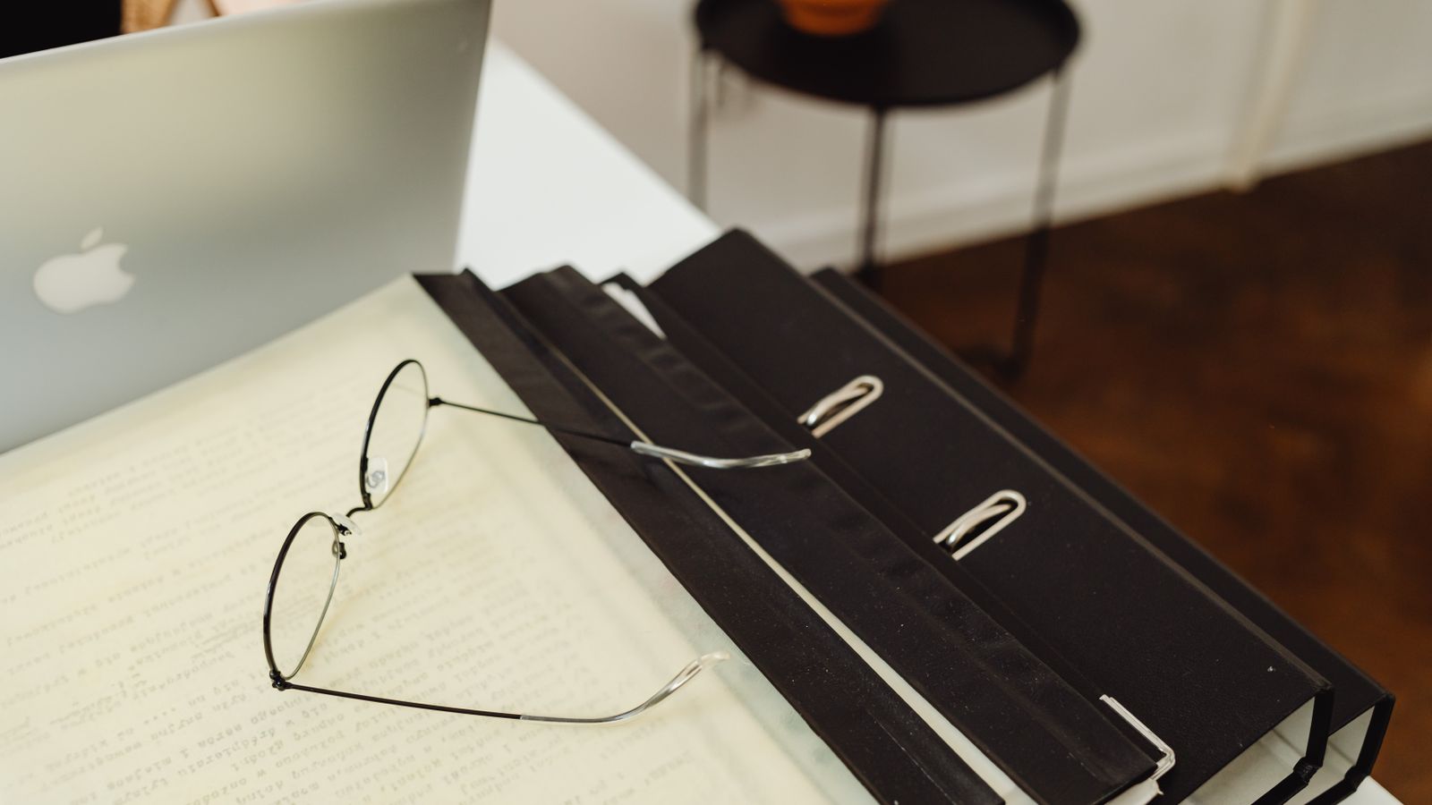 A neat office setup with binders, eyeglasses, and a laptop, perfect for productivity.